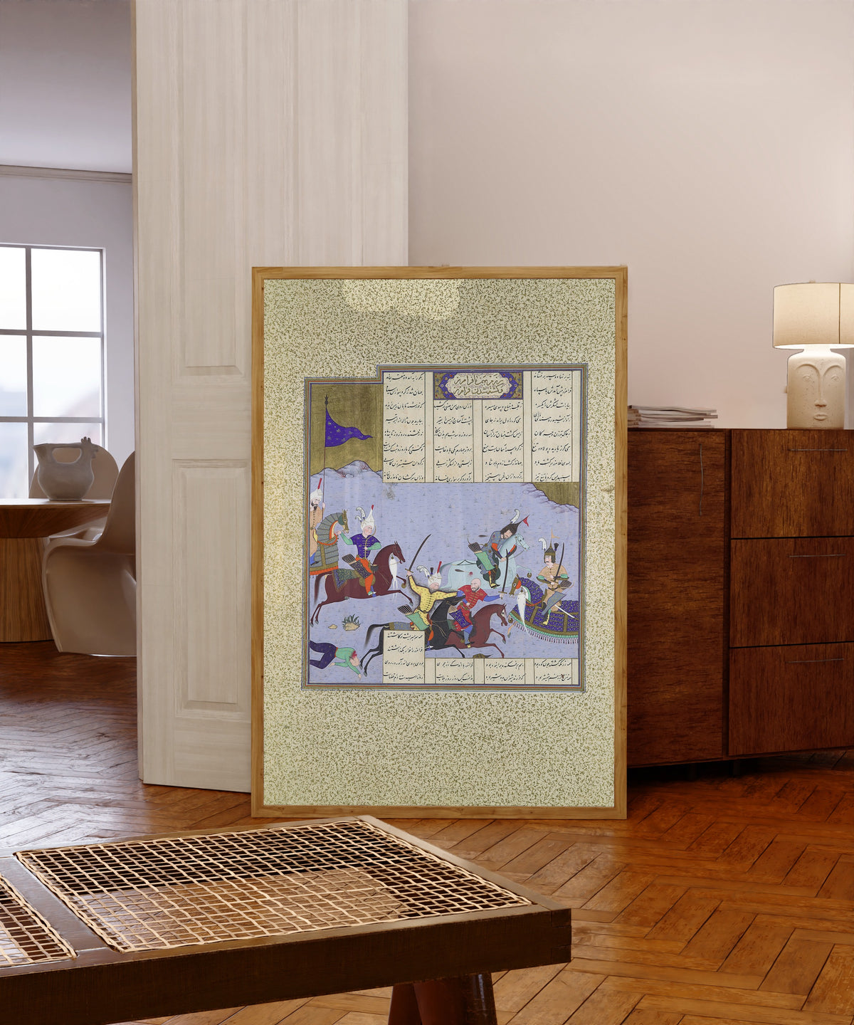 Framed art print of Shahnama of Shah Tahmasp: Faramarz Encircled… by Aqa Mirak (attributed), in a light wood frame leaning in a warm room with a parquet floor