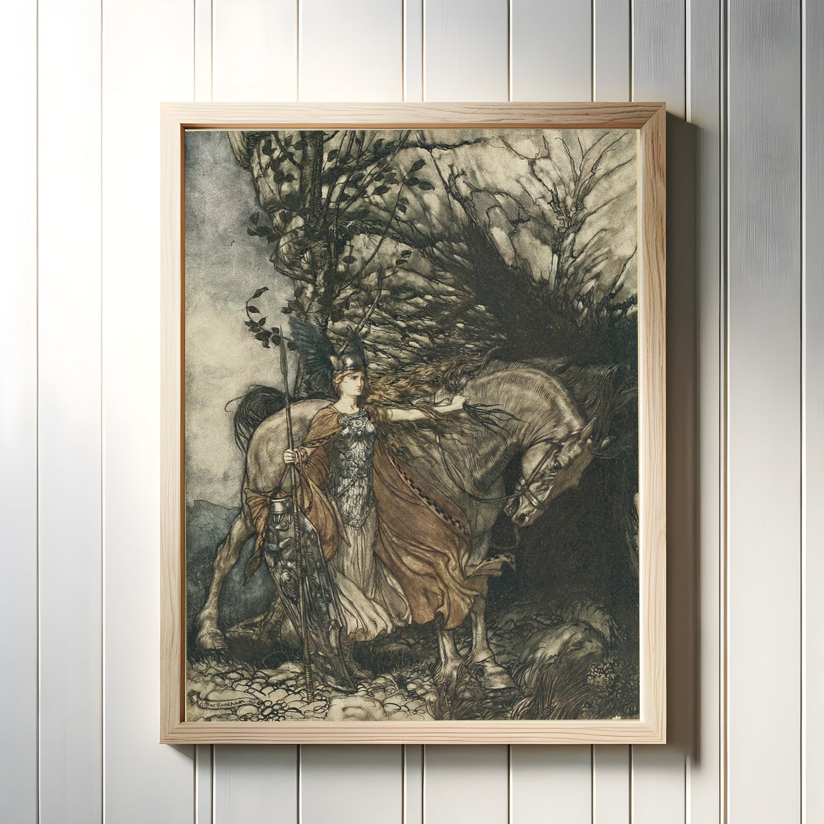 Framed art print of Brünnhilde with Her Horse, at the Mouth of the Cave by Arthur Rackham, in a light wood frame on a white panelled wall