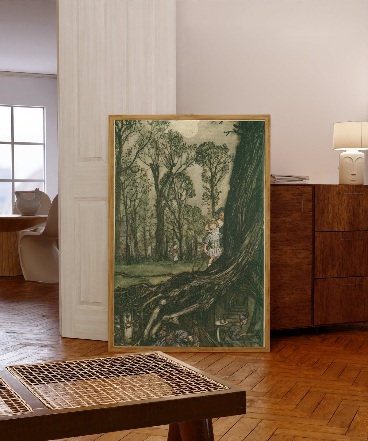 Framed art print of Fairies Are All More or Less in Hiding Until Dusk by Arthur Rackham, in a light wood frame leaning in a warm room with a parquet floor