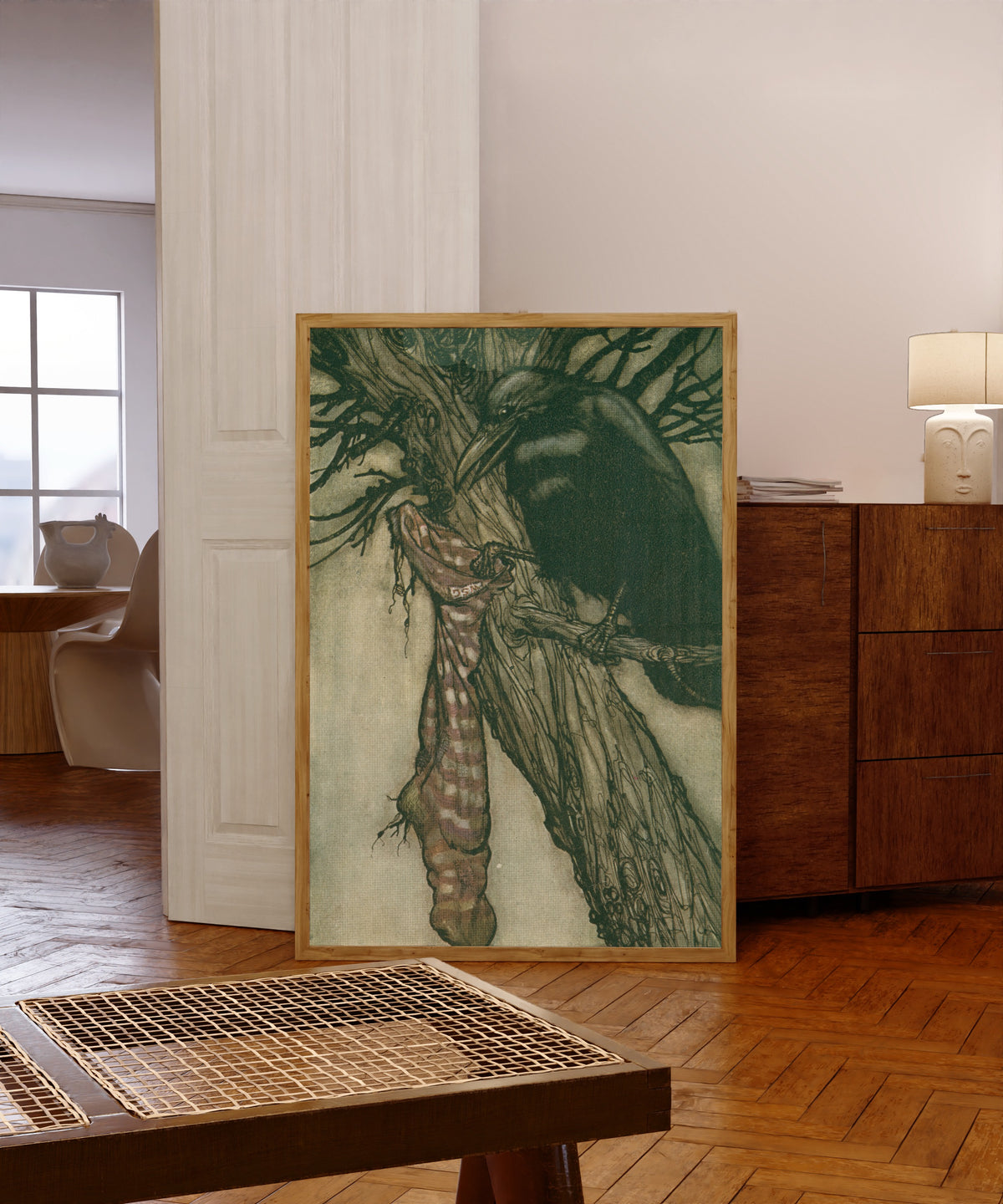 Framed art print of For Years He Had Been Quietly Filling His Stocking by Arthur Rackham, in a light wood frame leaning in a warm room with a parquet floor