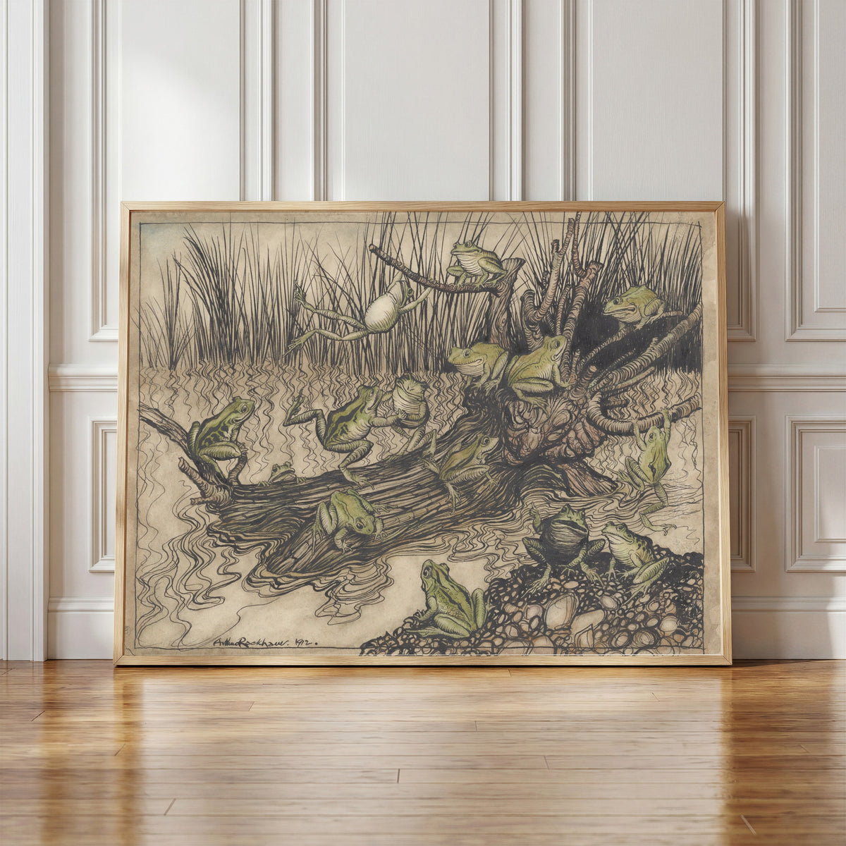 Framed art print of King Log by Arthur Rackham, in a light wood frame leaning against a panelled white wall