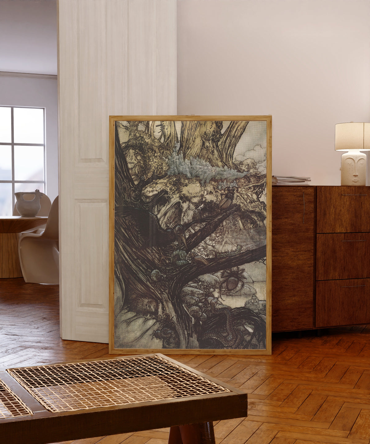 Framed art print of Never Harm, nor Spell, nor Charm by Arthur Rackham, in a light wood frame leaning in a warm room with a parquet floor