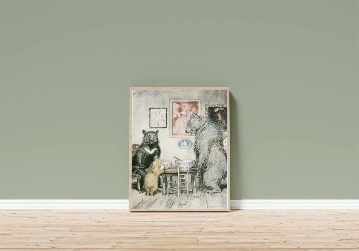 Framed art print of Somebody Has Been at My Porridge, and Has Eaten… by Arthur Rackham, in a light wood frame leaning on a sage green wall above a wooden floor