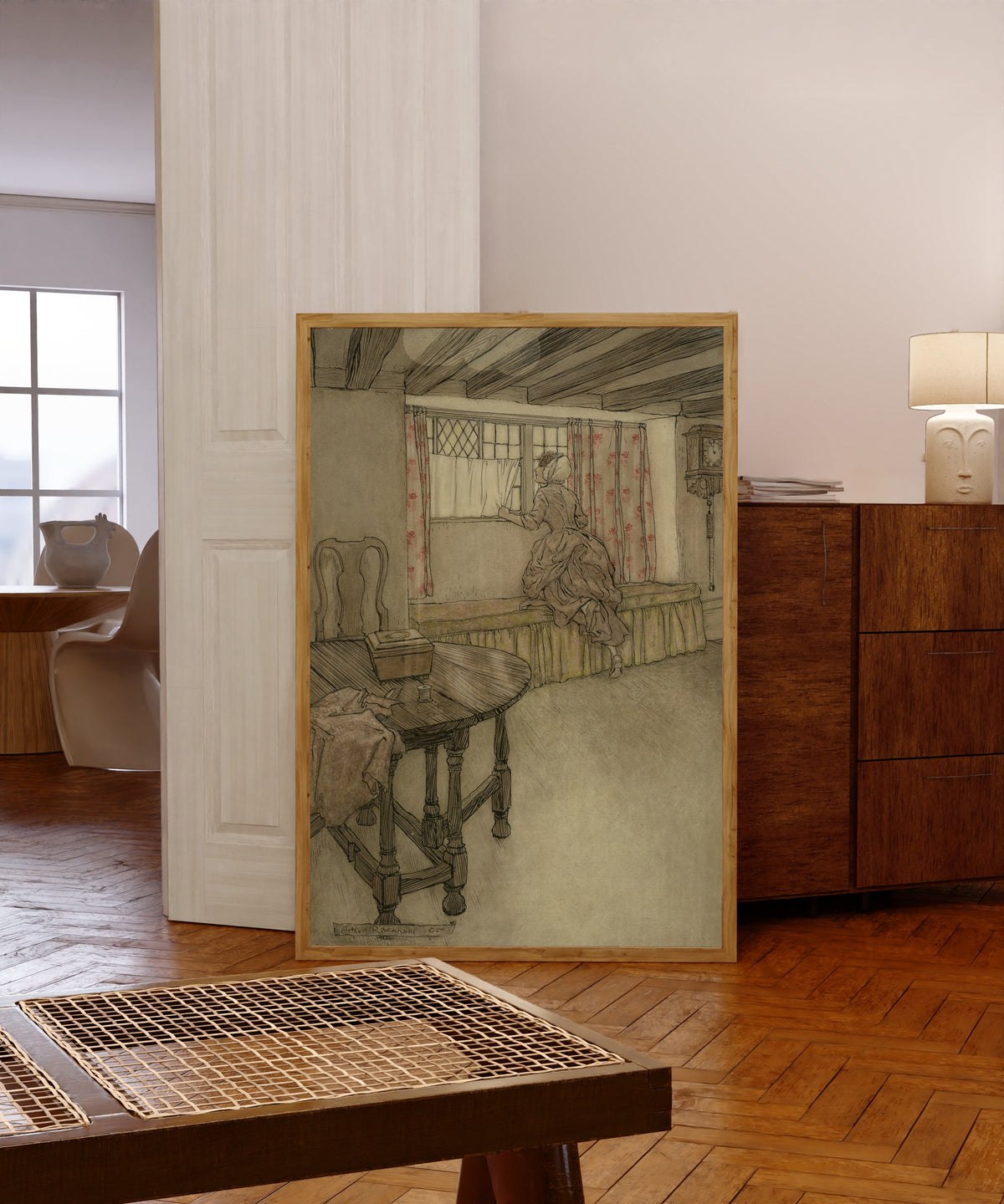 Framed art print of Strange Faces at the Windows by Arthur Rackham, in a light wood frame leaning in a warm room with a parquet floor