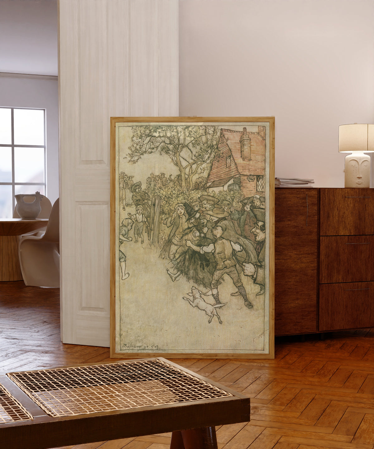 Framed art print of The Spectre of Tappington by Arthur Rackham, in a light wood frame leaning in a warm room with a parquet floor