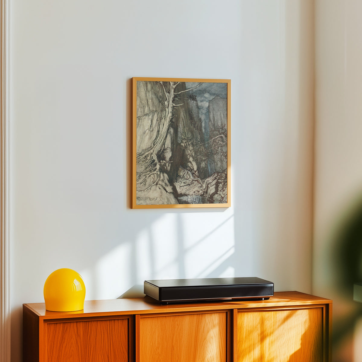 Framed art print of There as a Dread Dragon He Sojourns by Arthur Rackham, in a light wood frame on a white wall above an orange sideboard