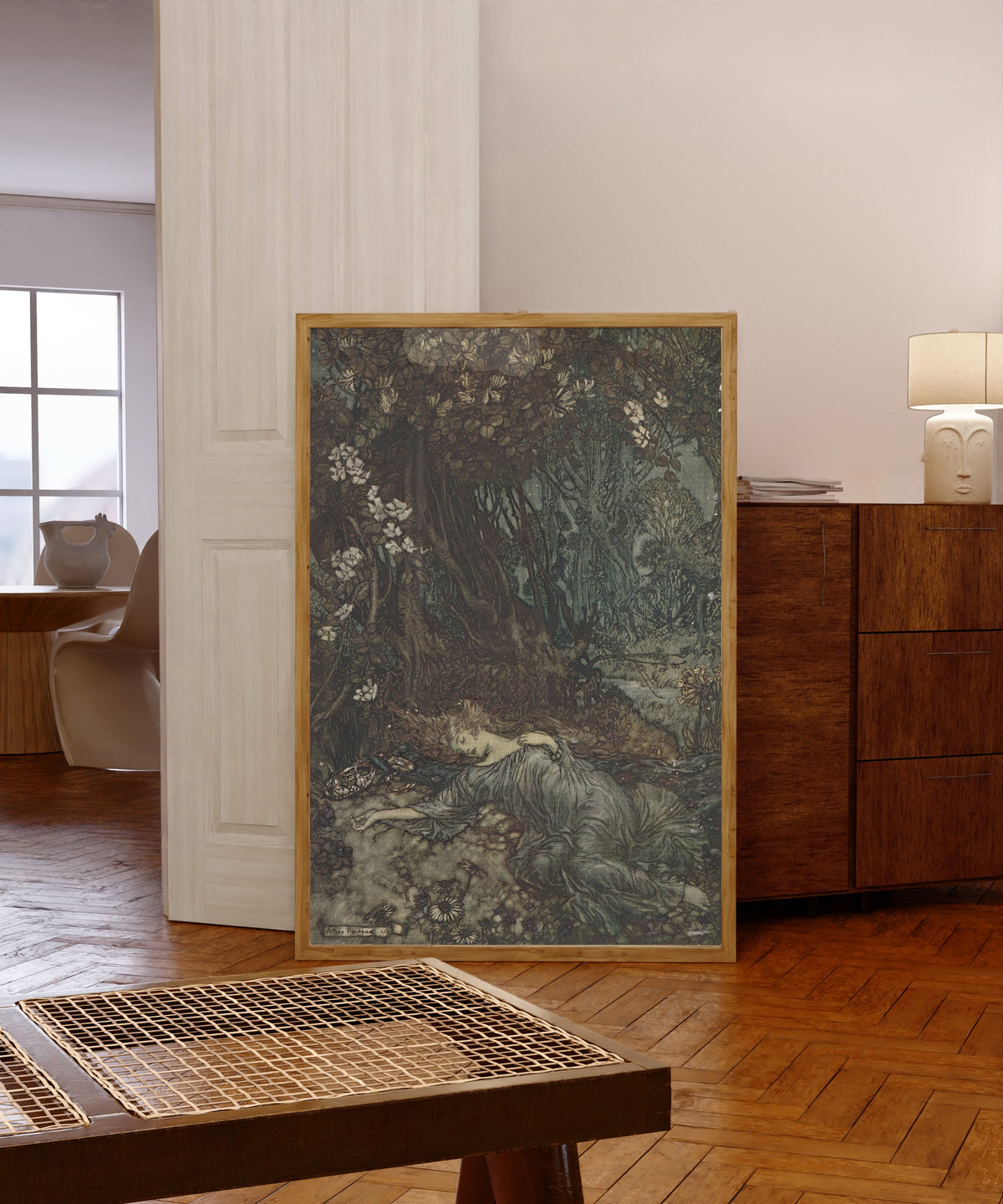 Framed art print of Titania Lying Asleep by Arthur Rackham, in a light wood frame leaning in a warm room with a parquet floor
