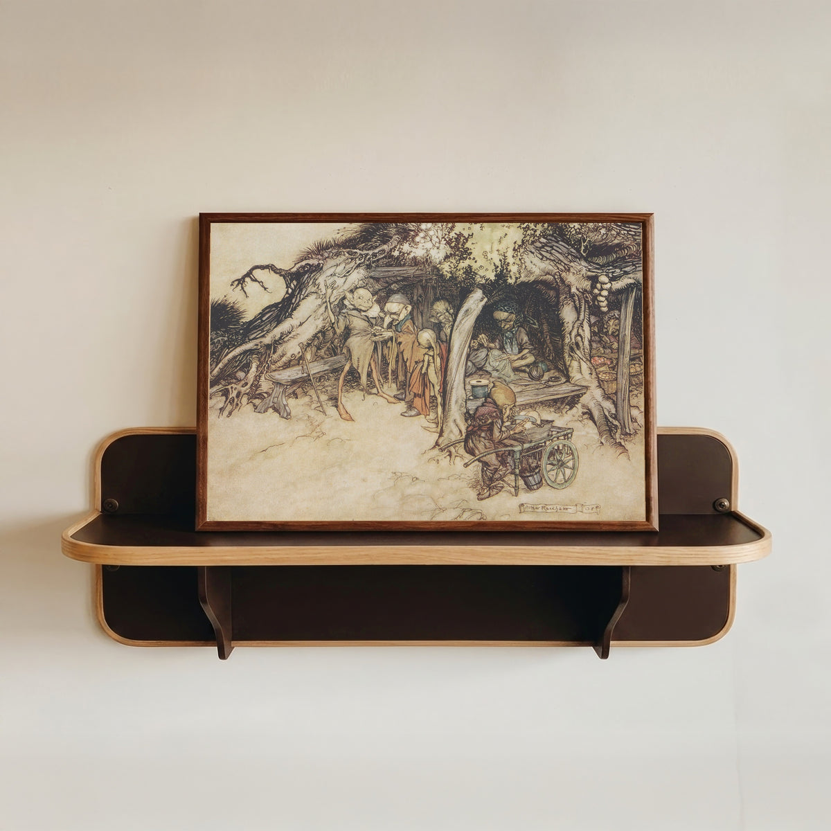 Framed art print of To Make My Small Elves Coats by Arthur Rackham, in a dark wood frame resting on a wall shelf