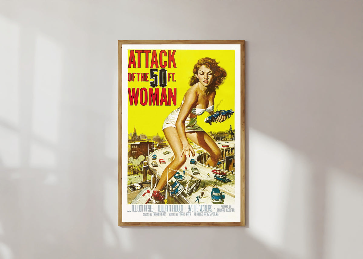 Framed art print of Attack of the 50 Foot Woman by Reynold Brown, in a light wood frame on a sunlit white wall