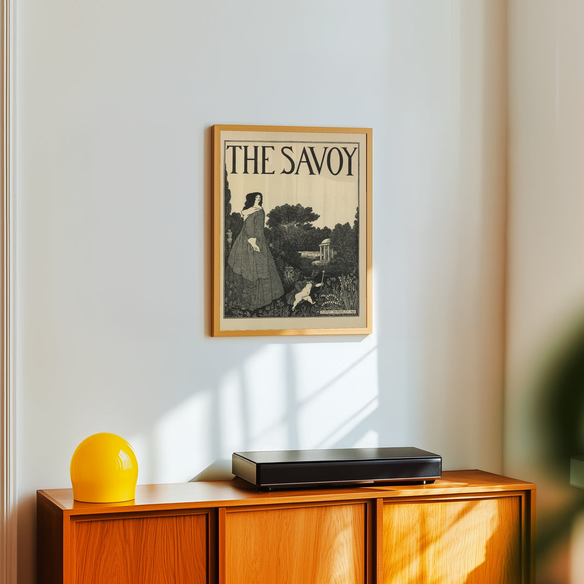 Framed art print of The Savoy: Cover Design for No. 1 by Aubrey Beardsley, in a light wood frame on a white wall above an orange sideboard