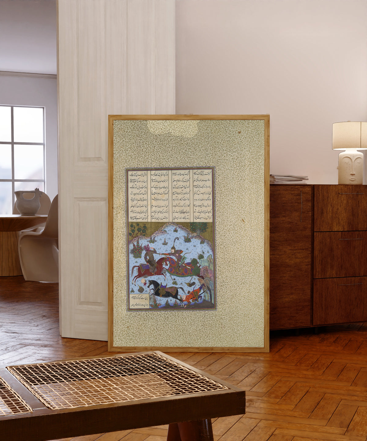 Framed art print of Shahnama of Shah Tahmasp: Gustaham Slays… by Bashdan Qara (attributed), in a light wood frame leaning in a warm room with a parquet floor