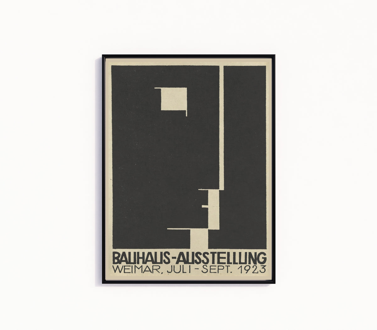 Framed art print of Ausstellung 1923 by Bauhaus, in a slim black frame on a plain white wall