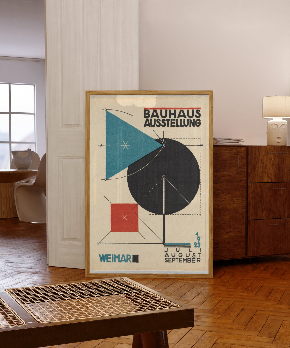 Framed art print of Ausstellung Poster by Bauhaus, in a light wood frame leaning in a warm room with a parquet floor