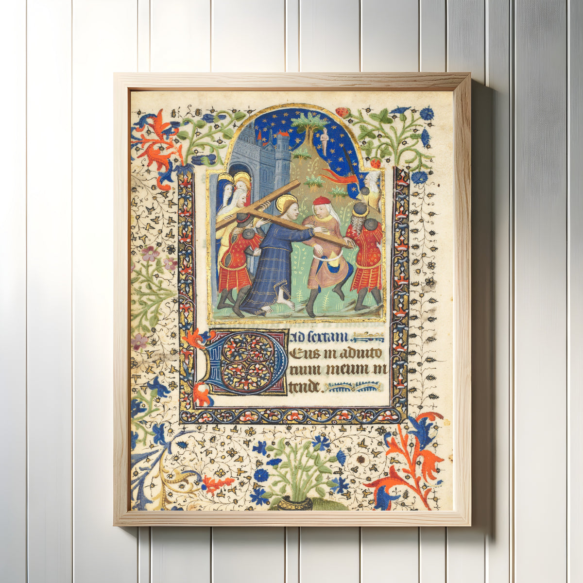 Framed art print of Book of Hours: Christ Carrying the Cross, in a light wood frame on a white panelled wall