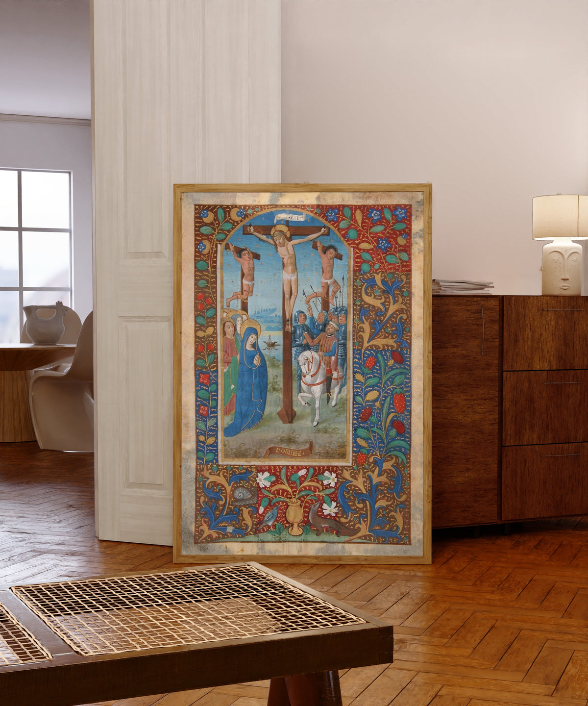 Framed art print of Book of Hours: The Crucifixion, in a light wood frame leaning in a warm room with a parquet floor