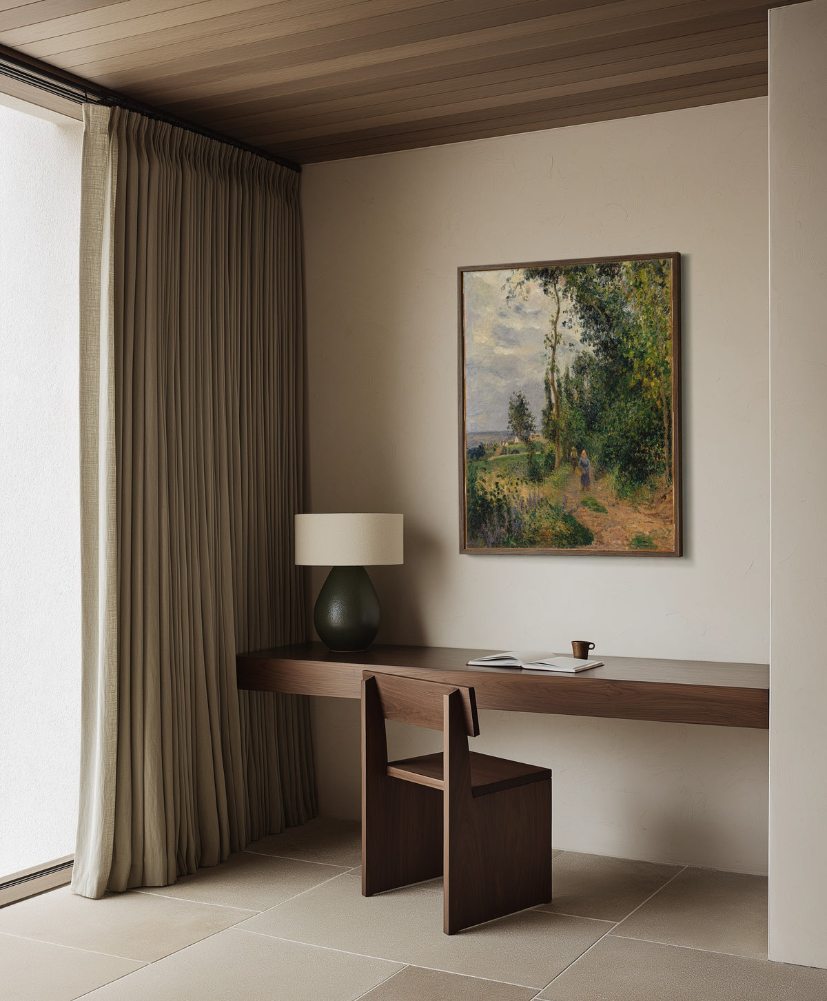 Framed art print of Côte des Grouettes, near Pontoise by Camille Pissarro, in a dark wood frame on a plaster wall above a walnut desk