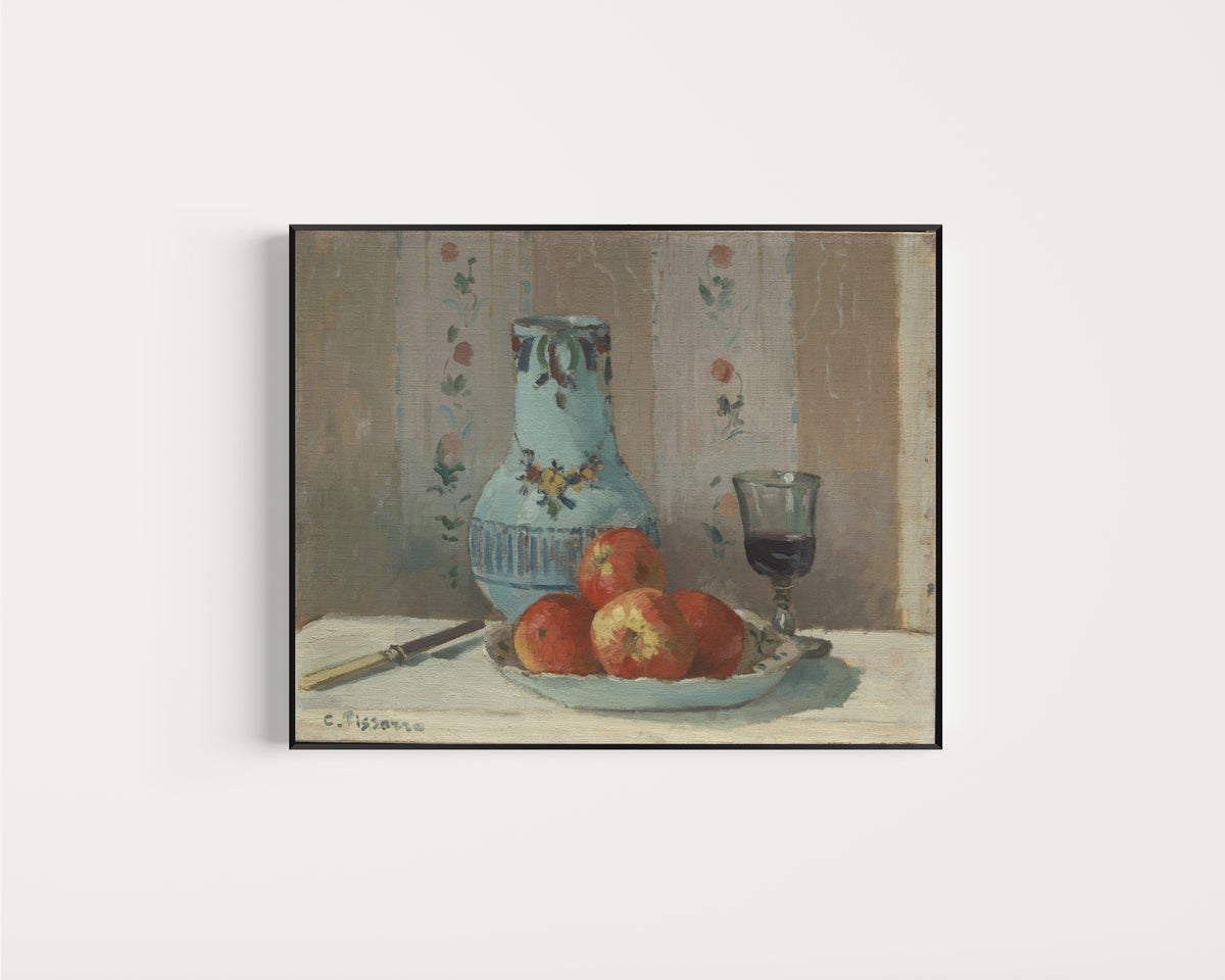 Framed art print of Still Life with Apples and Pitcher by Camille Pissarro, in a slim black frame on a plain white wall