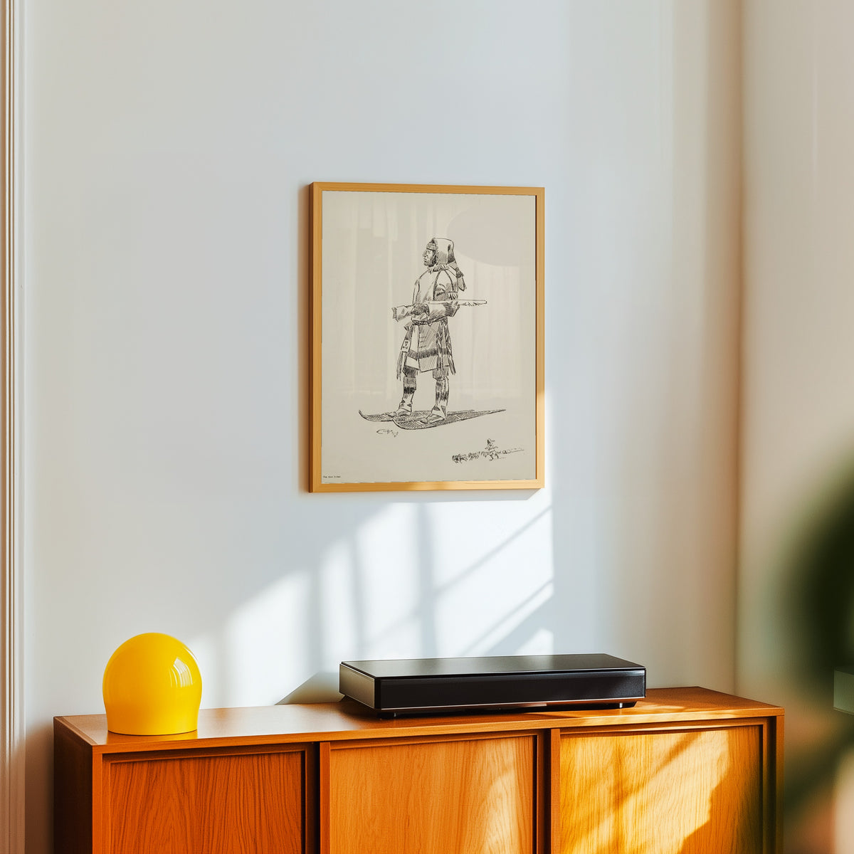 Framed art print of The Cree Indian by Charles M. Russell, in a light wood frame on a white wall above an orange sideboard