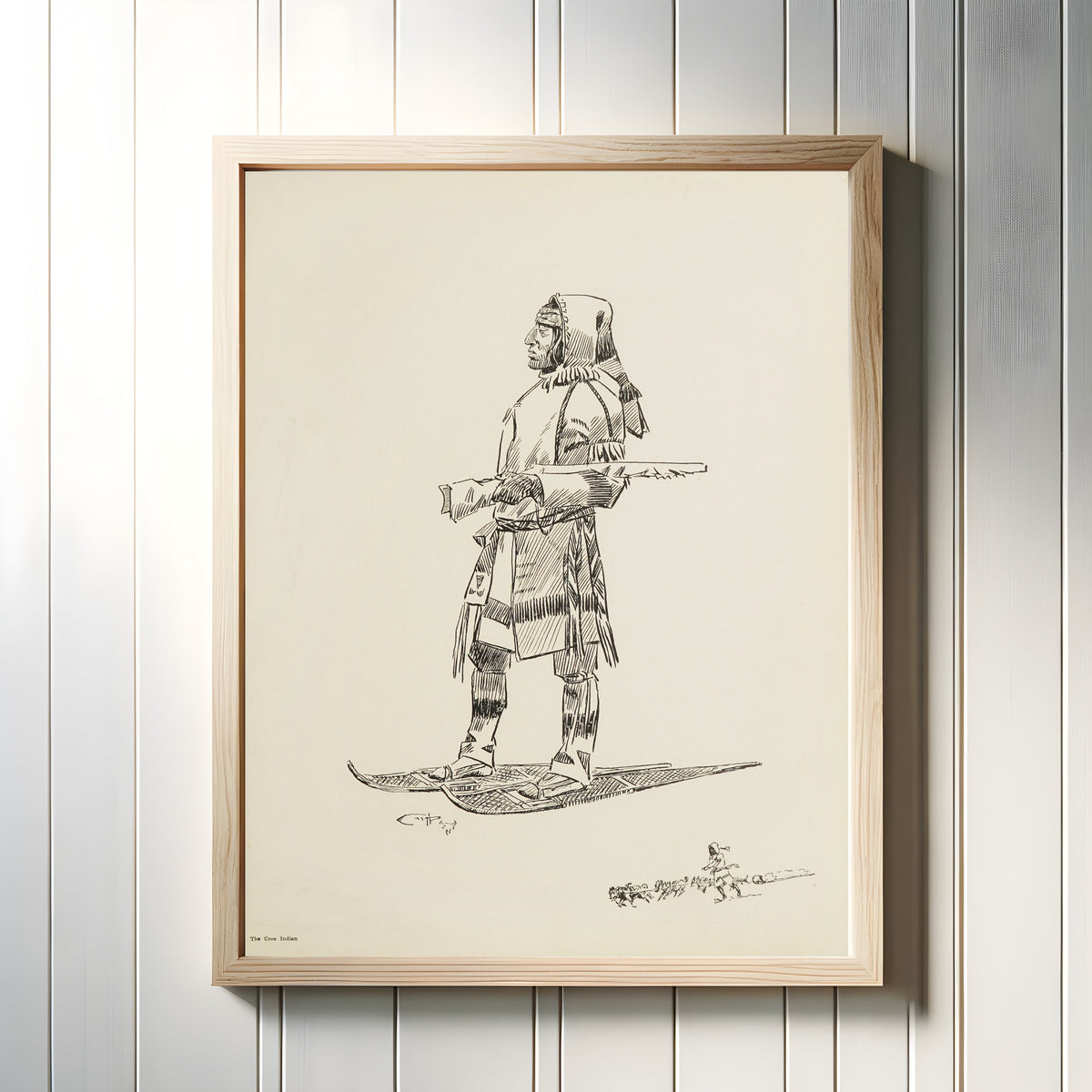 Framed art print of The Cree Indian by Charles M. Russell, in a light wood frame on a white panelled wall