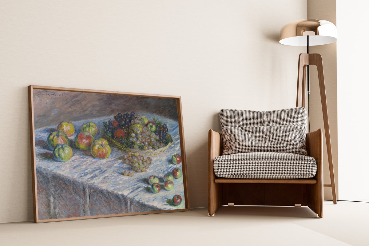 Apples and Grapes by Claude Monet — framed and leaning against a wall beside an armchair and a floor lamp