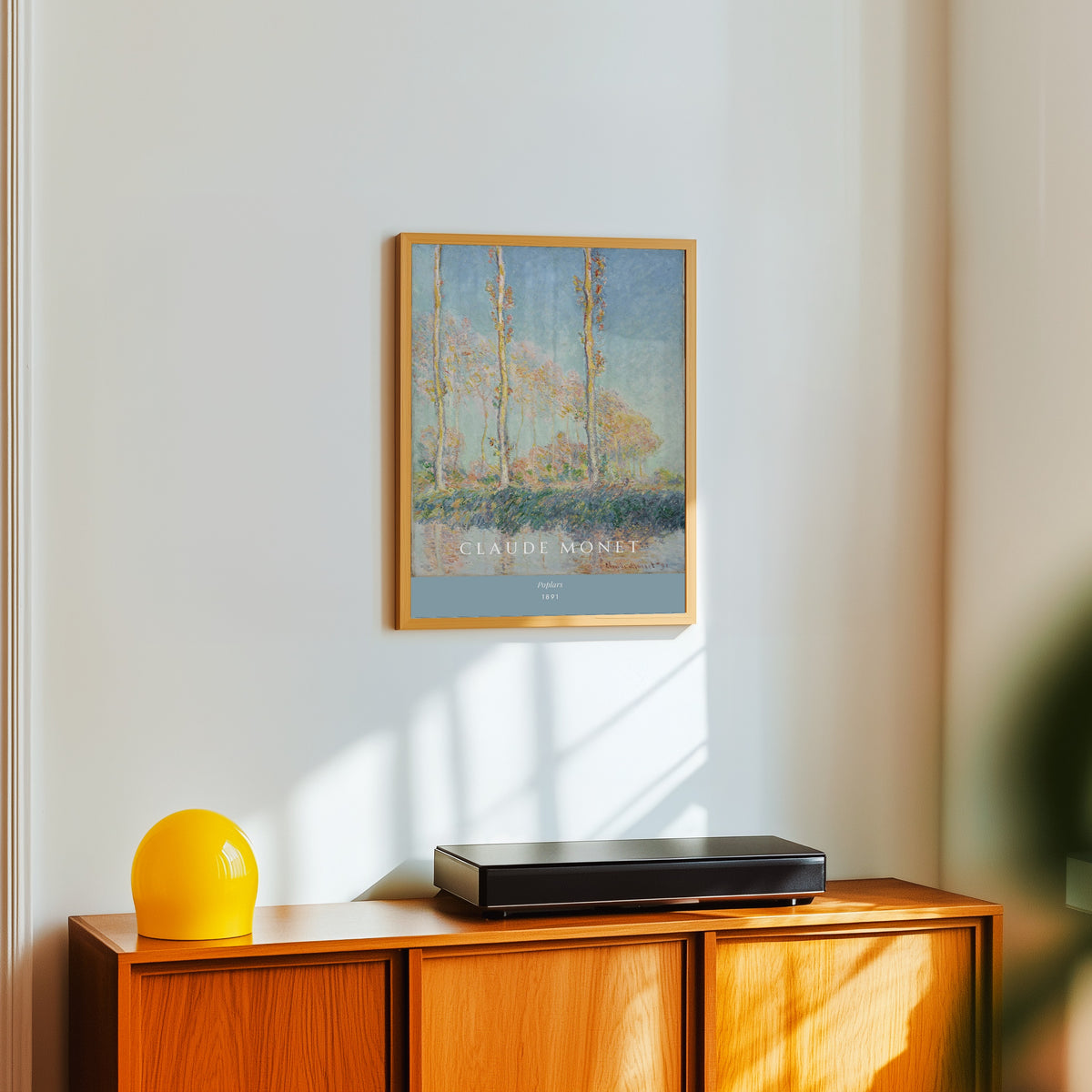Framed art print of Poplars by Claude Monet, in a light wood frame on a white wall above an orange sideboard