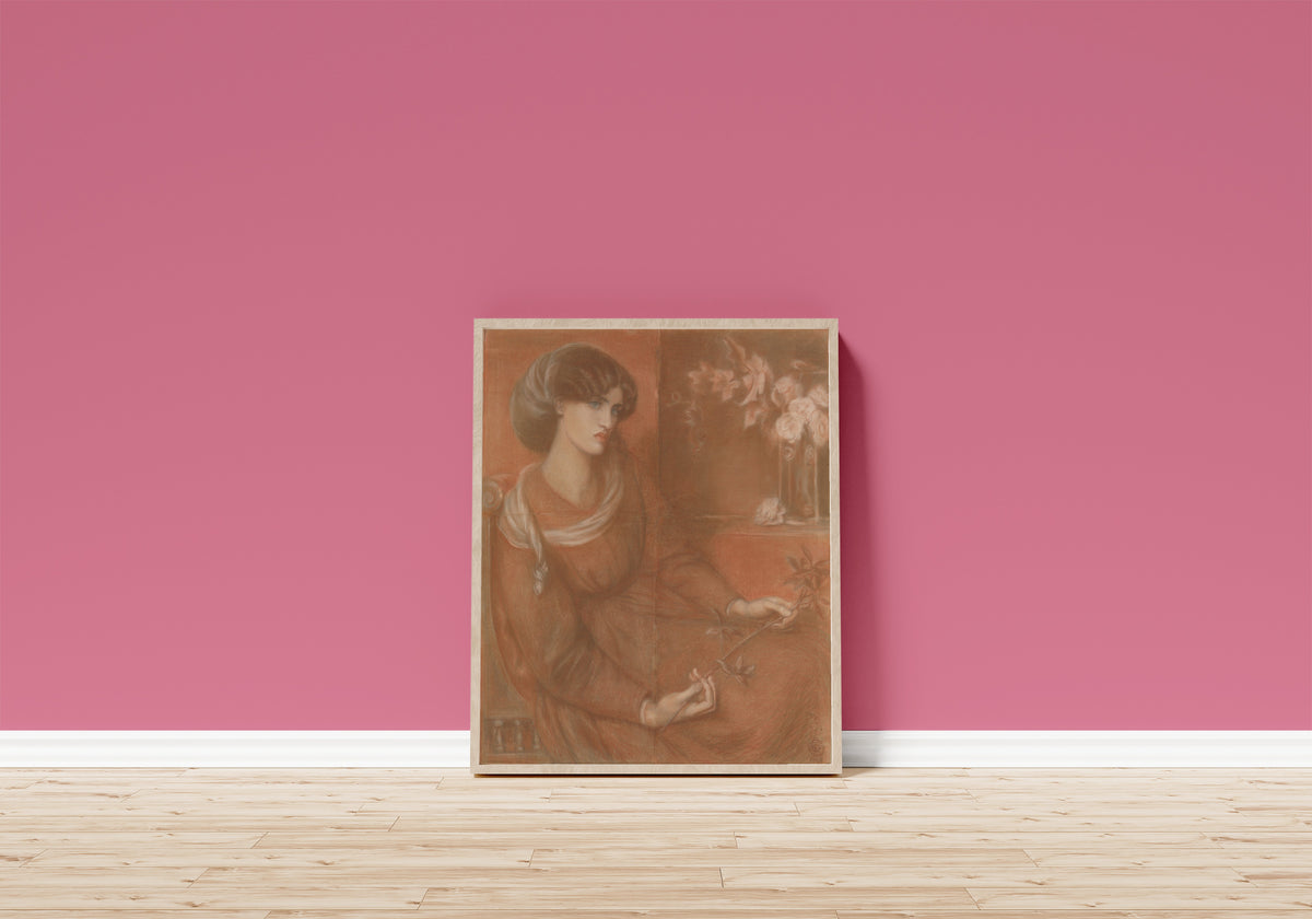 Framed art print of Jane Morris: Study for Mariana by Dante Gabriel Rossetti, in a light wood frame leaning on a pink wall above a wooden floor