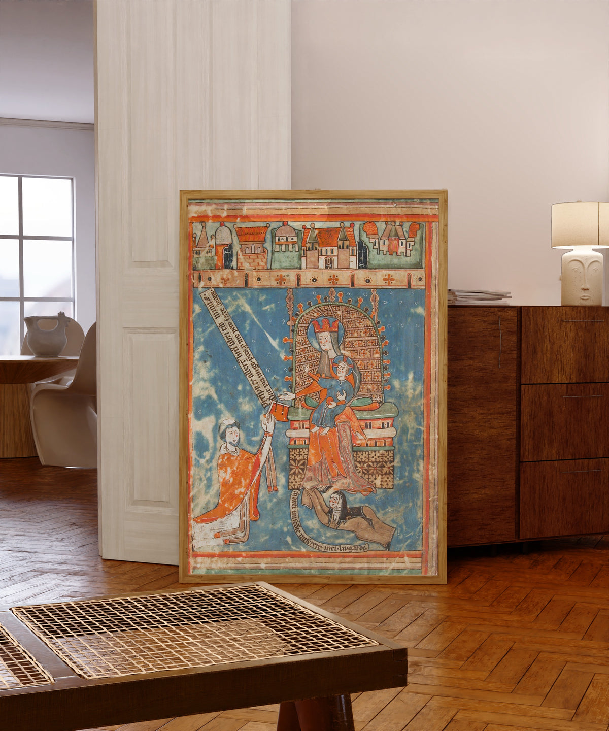 Framed art print of Dedication of a Book to the Virgin, in a light wood frame leaning in a warm room with a parquet floor