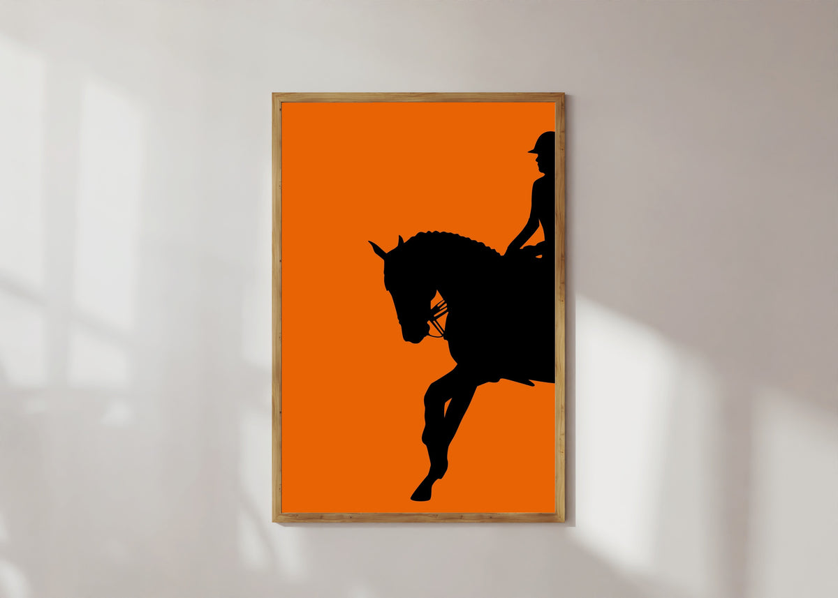 Framed art print of Horse and Rider in Orange by Vintage Poster, in a light wood frame on a sunlit white wall