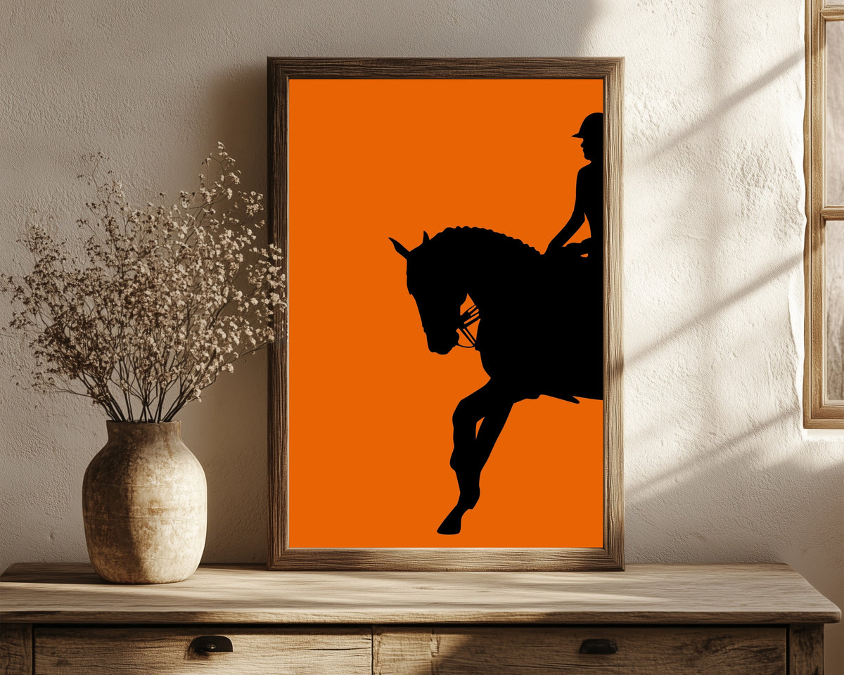 Framed art print of Horse and Rider in Orange by Vintage Poster, in a dark wood frame leaning on a rustic console beside dried flowers