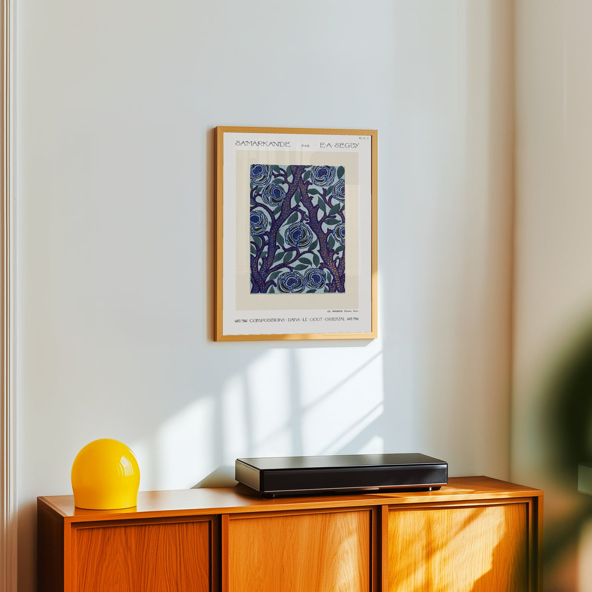 Framed art print of Samarkande, Plate 13 by E. A. Séguy, in a light wood frame on a white wall above an orange sideboard