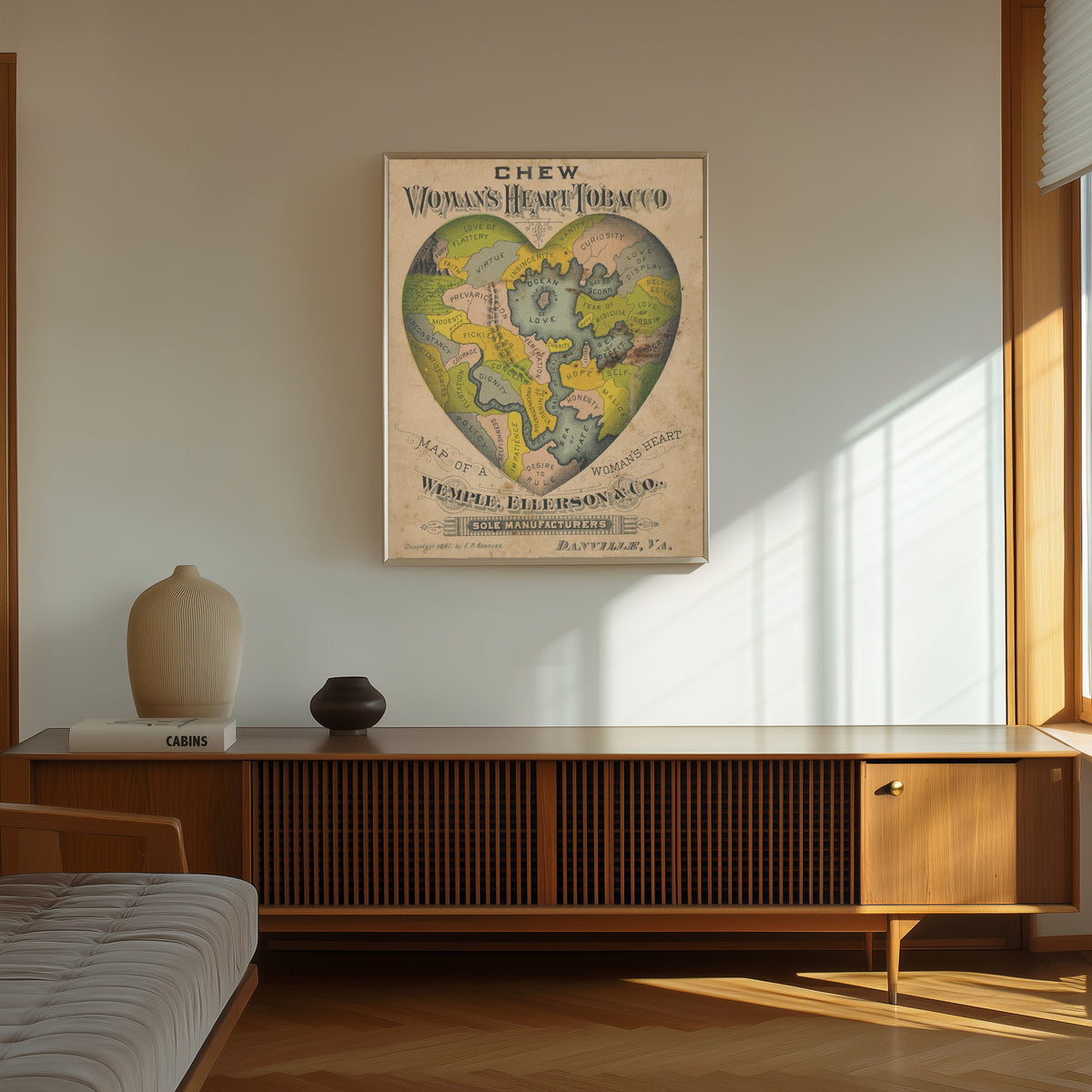 Framed art print of Map of a Woman's Heart by E.P. Beadles, in a thin light frame on a sunlit wall above a wooden sideboard