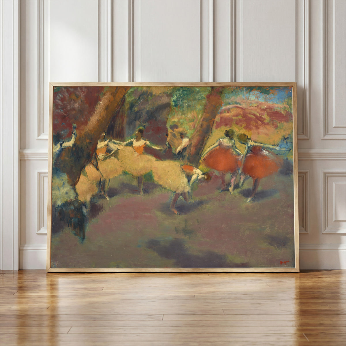 Framed art print of Before the Performance by Edgar Degas, in a light wood frame leaning against a panelled white wall