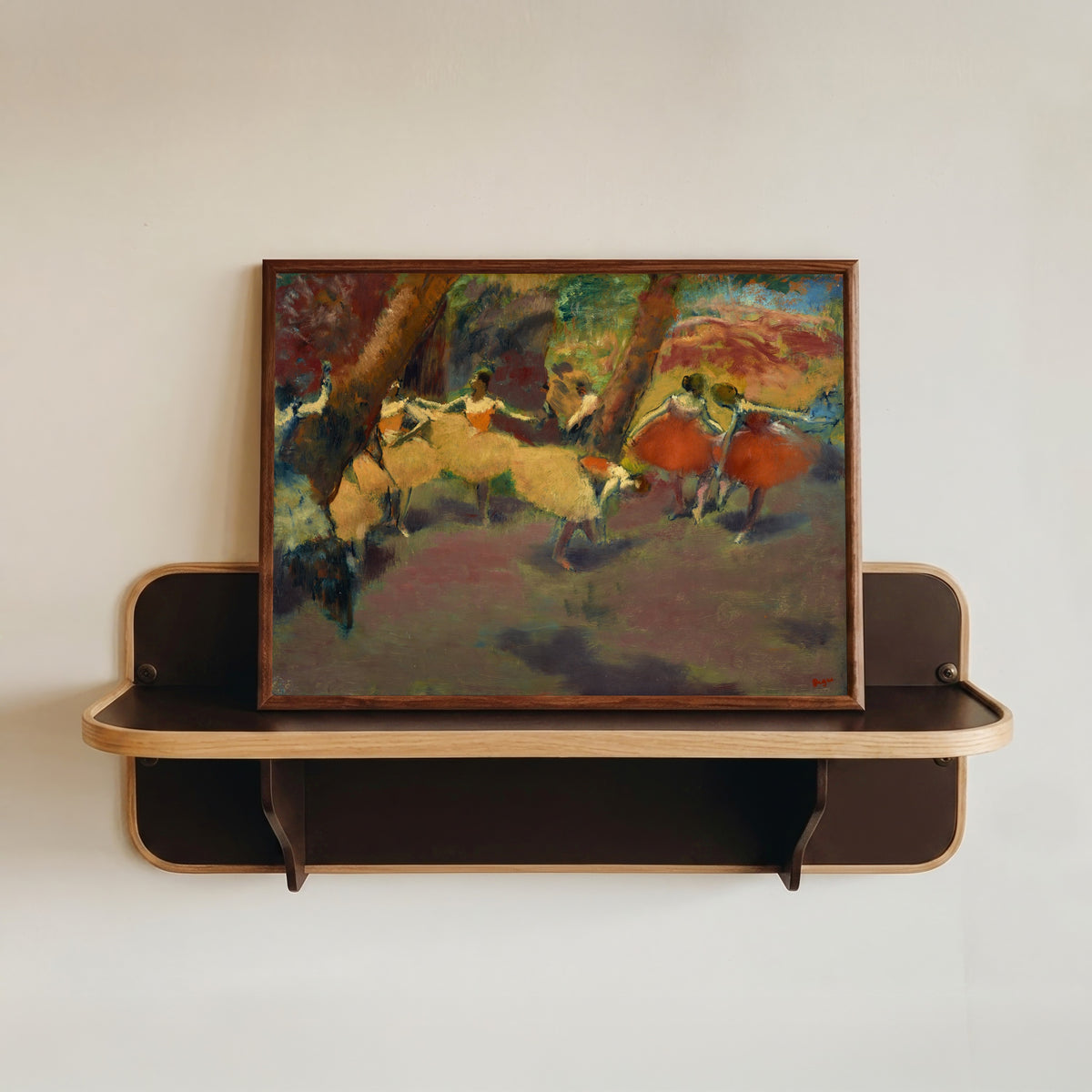 Framed art print of Before the Performance by Edgar Degas, in a dark wood frame resting on a wall shelf