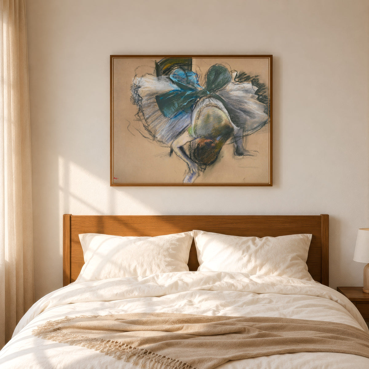 Framed art print of Dancer Adjusting Her Slipper (Blue and Green Bow) by Edgar Degas, in a slim wood frame above a bed in a sunlit bedroom