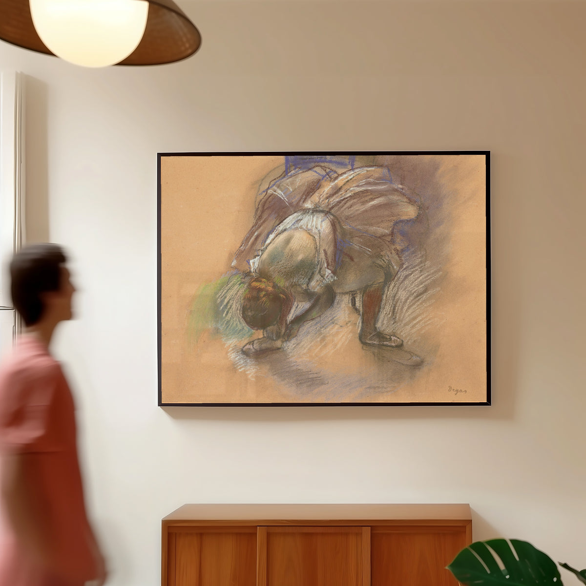 Framed art print of Dancer Adjusting Her Slipper (Lilac Tutu) by Edgar Degas, in a slim black frame on a warm wall in a sunlit room
