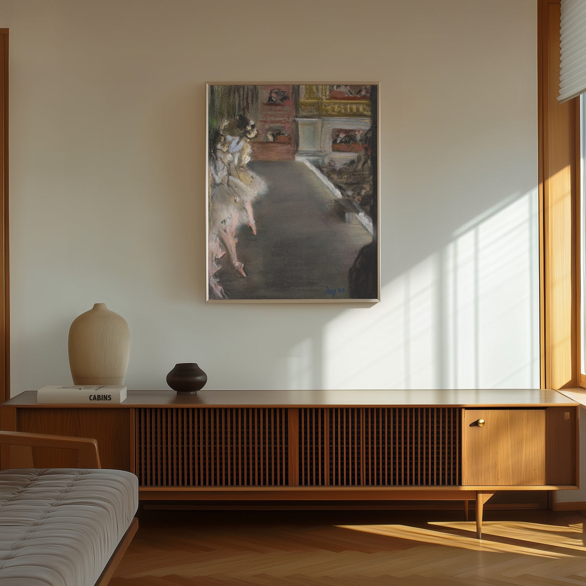 Framed art print of Dancers at the Old Opera House by Edgar Degas, in a thin light frame on a sunlit wall above a wooden sideboard