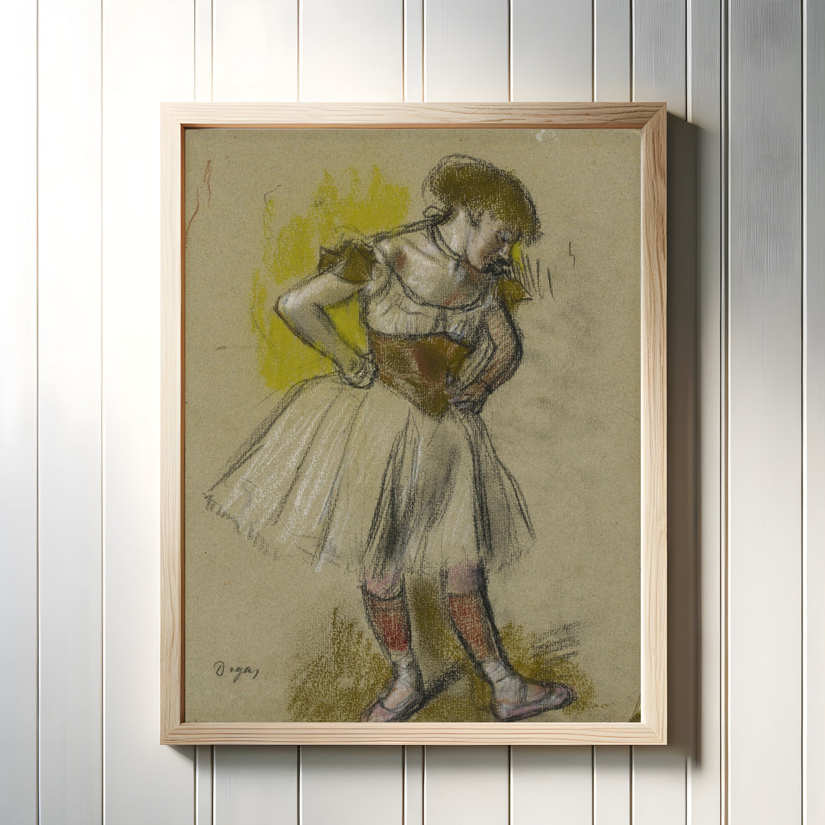 Framed art print of Danseuse (Hands on Hips) by Edgar Degas, in a light wood frame on a white panelled wall