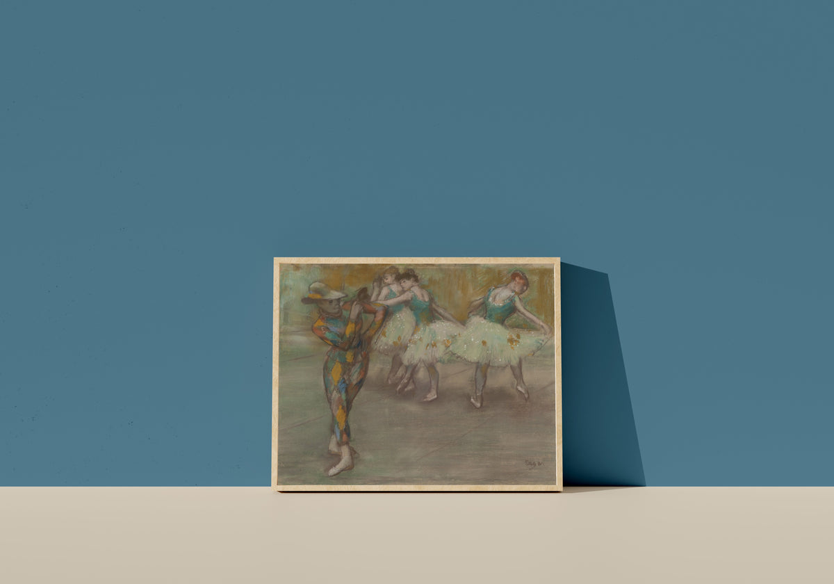 Framed art print of Harlequin Dance by Edgar Degas, in a light wood frame leaning on a blue wall