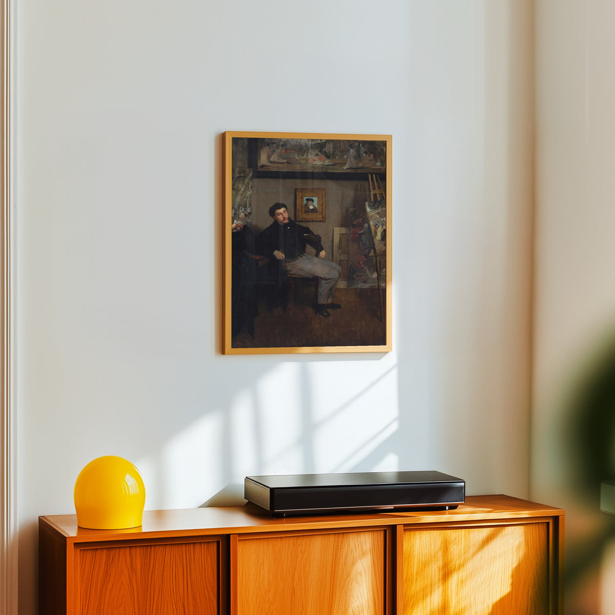 Framed art print of James-Jacques-Joseph Tissot by Edgar Degas, in a light wood frame on a white wall above an orange sideboard