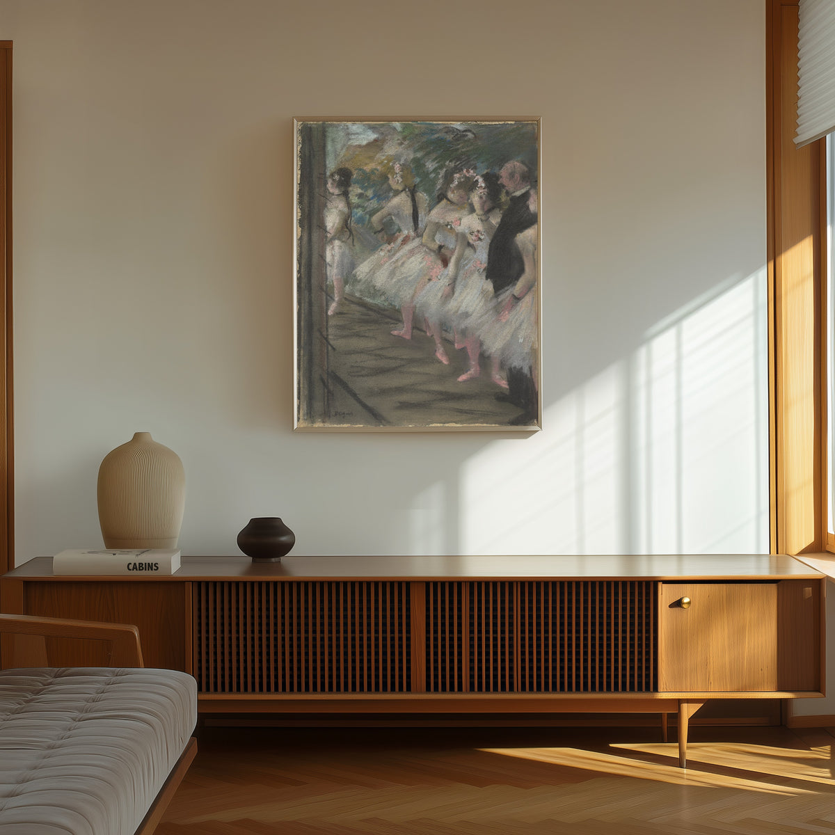 Framed art print of The Ballet by Edgar Degas, in a thin light frame on a sunlit wall above a wooden sideboard