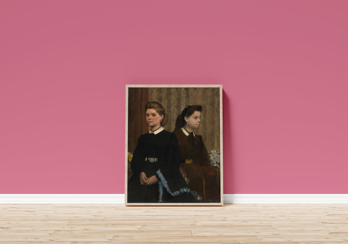 Framed art print of The Bellelli Sisters (Giovanna and Giuliana Bellelli) by Edgar Degas, in a light wood frame leaning on a pink wall above a wooden floor