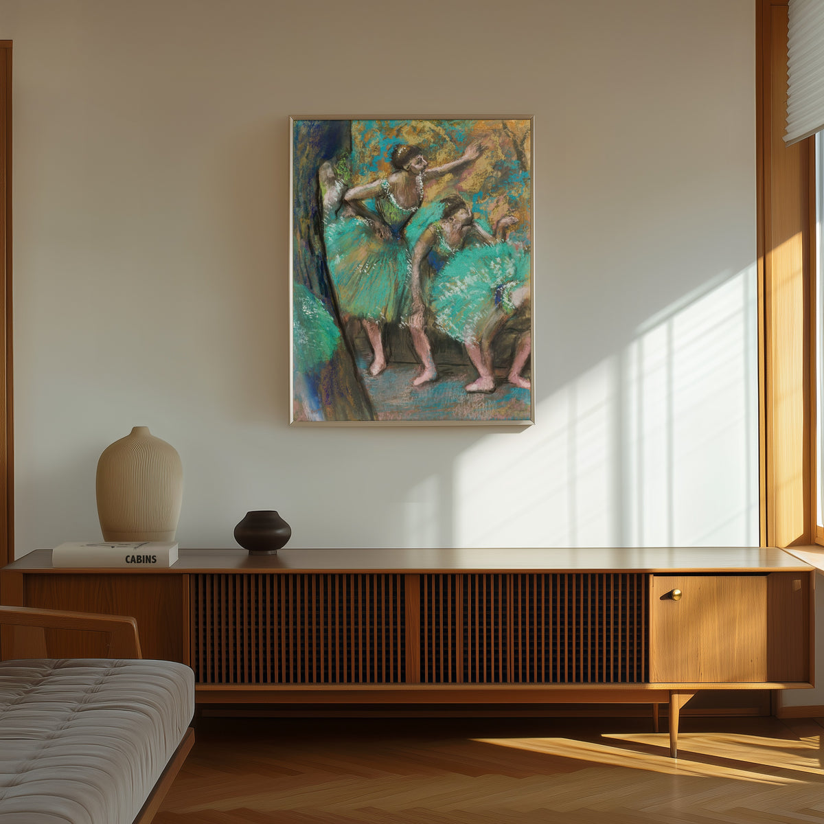 Framed art print of The Dancers (Turquoise Skirts) by Edgar Degas, in a thin light frame on a sunlit wall above a wooden sideboard