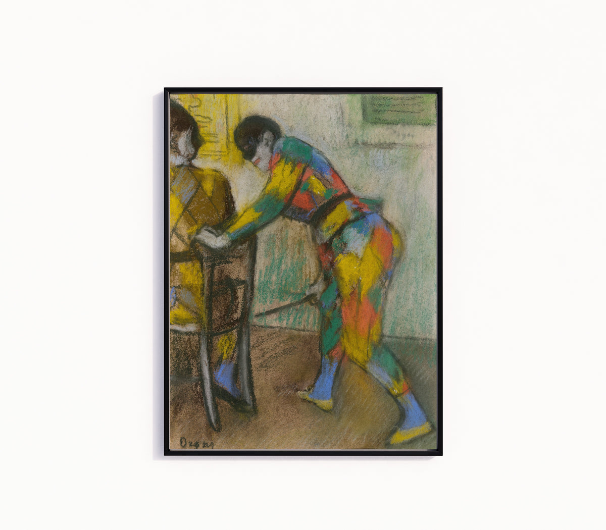 Framed art print of Two Harlequins by Edgar Degas, in a slim black frame on a plain white wall
