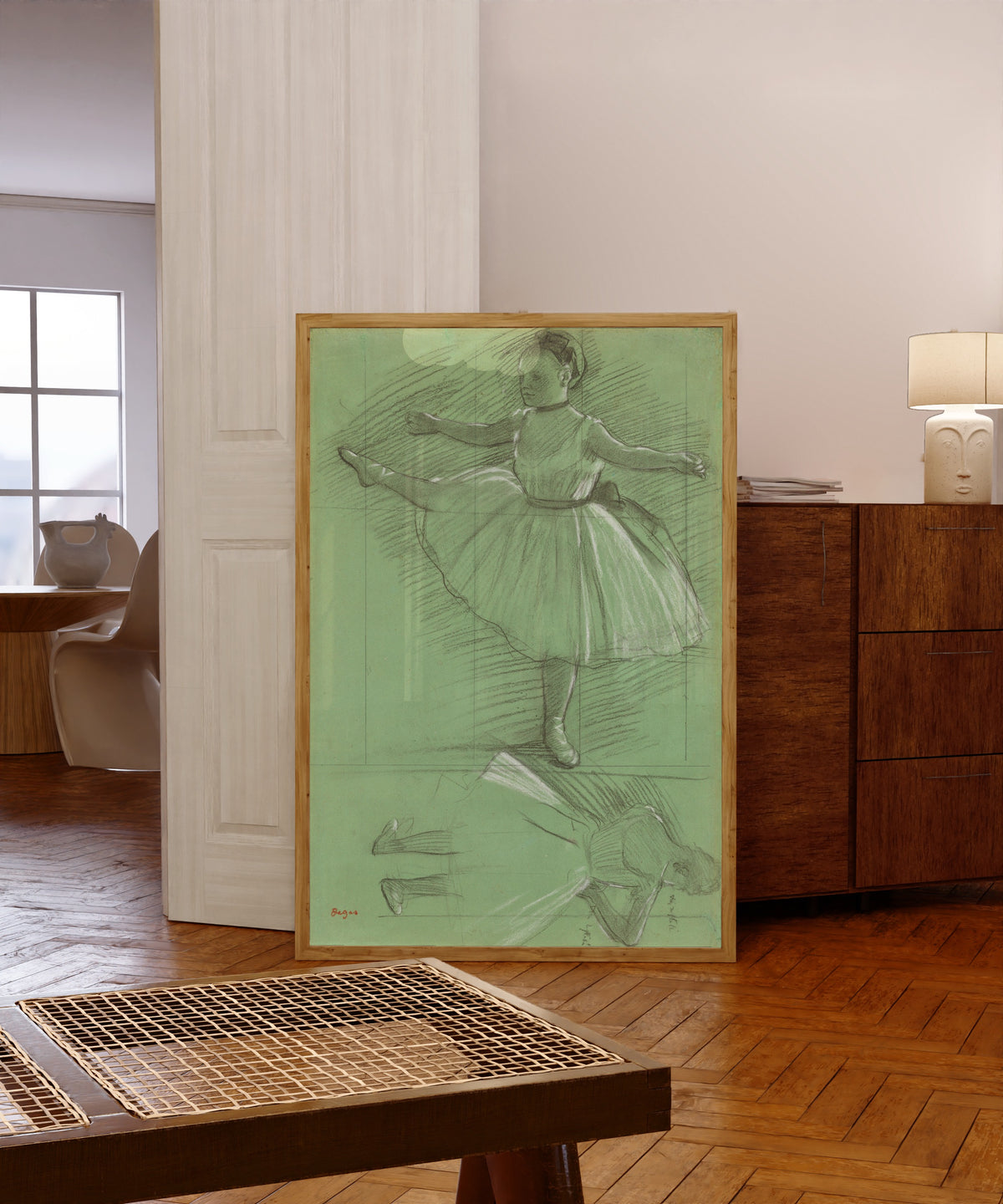 Framed art print of Two Studies of Dancers (Leg Raised to the Side) by Edgar Degas, in a light wood frame leaning in a warm room with a parquet floor