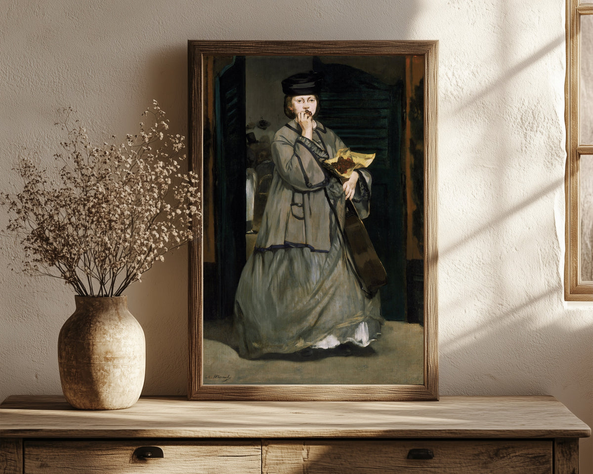 Framed art print of Street Singer by Édouard Manet, in a dark wood frame leaning on a rustic console beside dried flowers