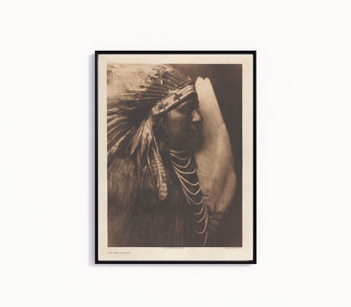 Framed art print of Nez Percé Brave by Edward S. Curtis, in a slim black frame on a plain white wall