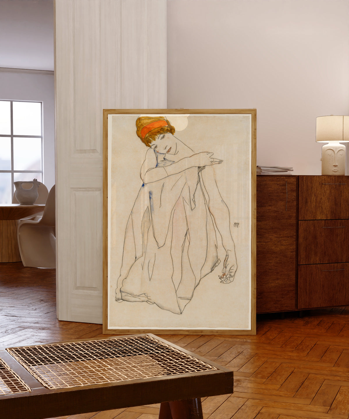 Framed art print of Dancer (Die Tänzerin) by Egon Schiele, in a light wood frame leaning in a warm room with a parquet floor
