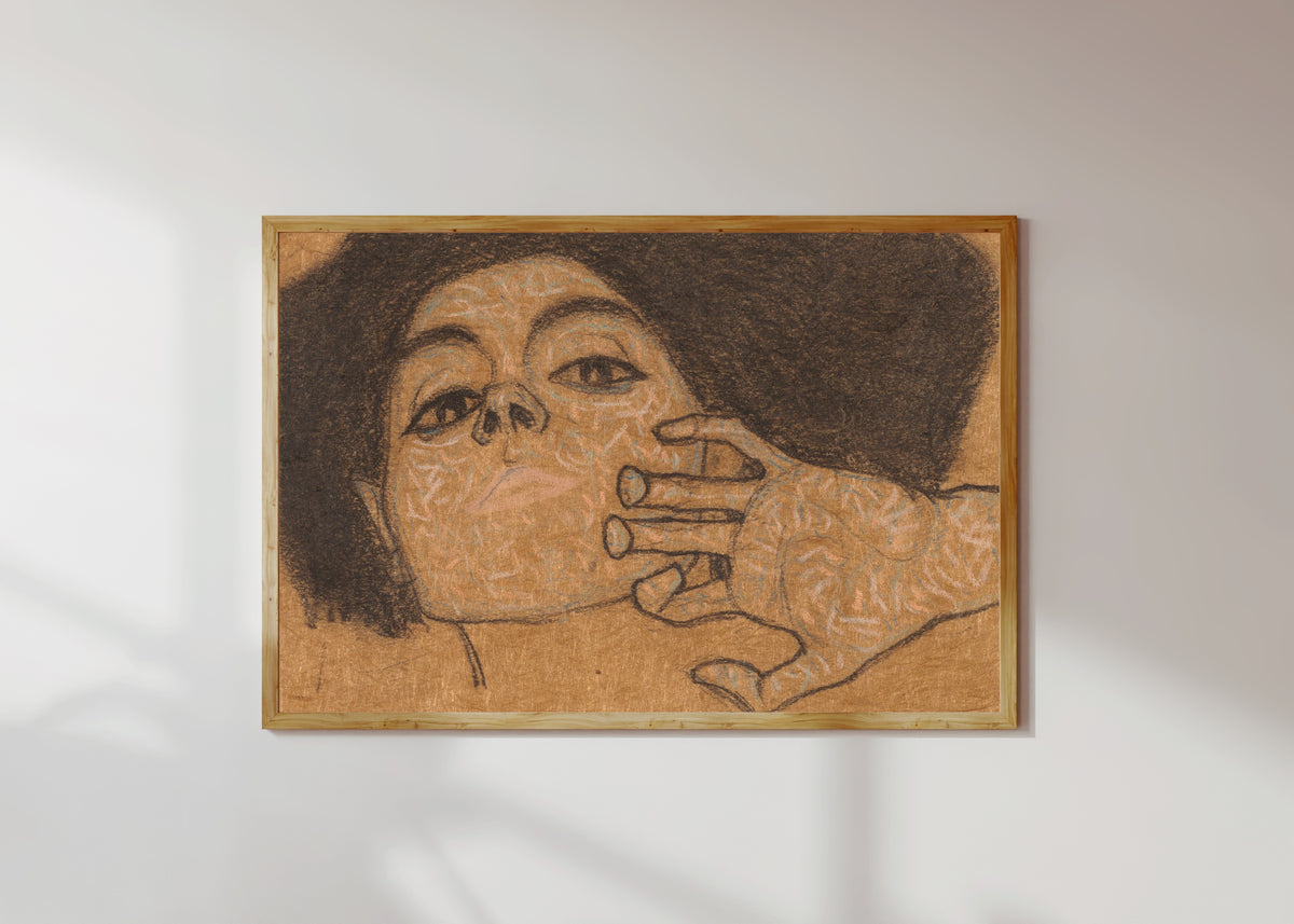 Framed art print of Head of a Woman by Egon Schiele, in a light wood frame on a sunlit white wall
