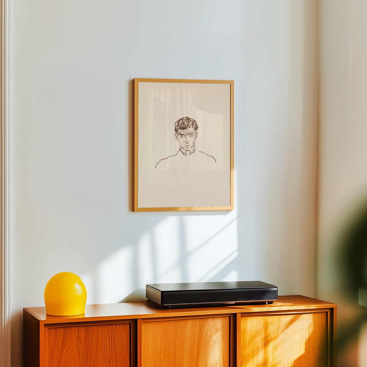 Framed art print of Portrait of Paris von Gütersloh by Egon Schiele, in a light wood frame on a white wall above an orange sideboard