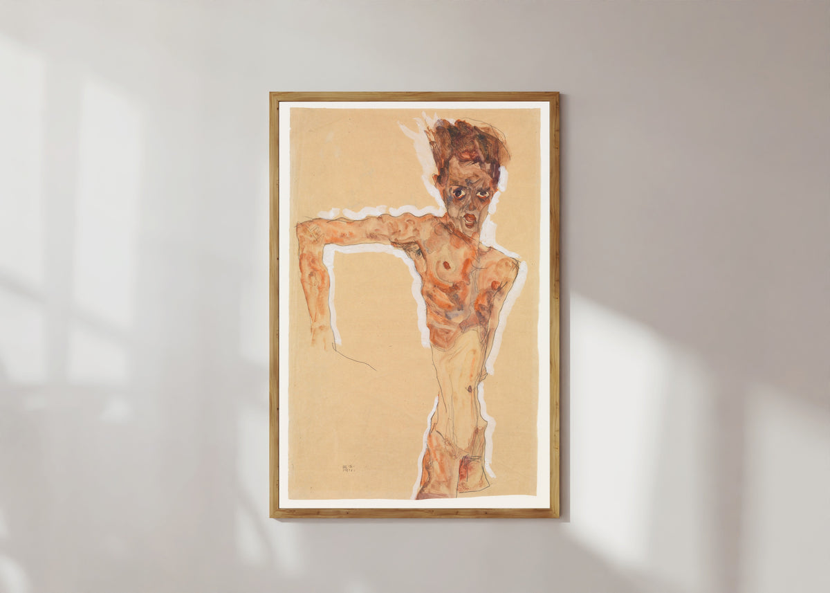 Framed art print of Self-Portrait by Egon Schiele, in a light wood frame on a sunlit white wall